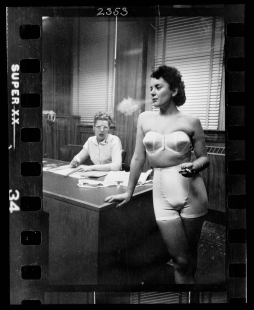 Woman model, standing in an office, smoking while modeling undergarments