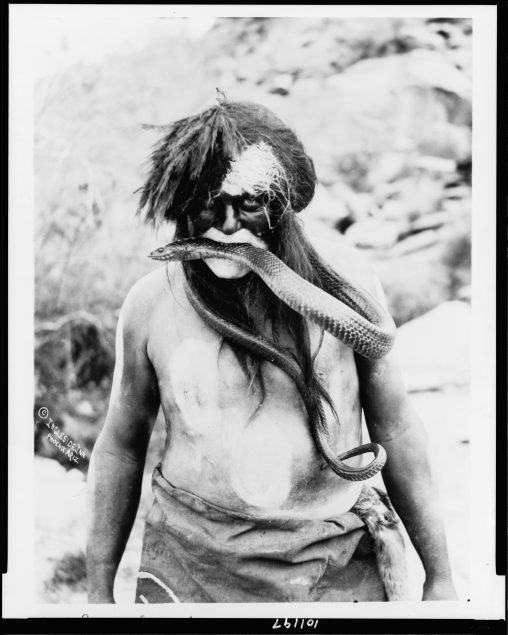 Hopi man with painted face and body and snake in mouth, Arizona, c.1924.