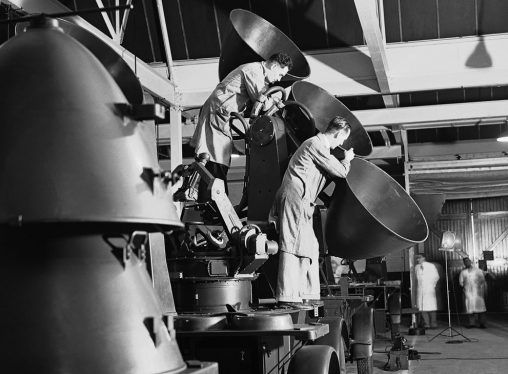Workmen fit a set of paraboloids in a sound detector for use by anti-aircraft batteries guarding the skies England, in a factory somewhere in England, on July 30, 1940.