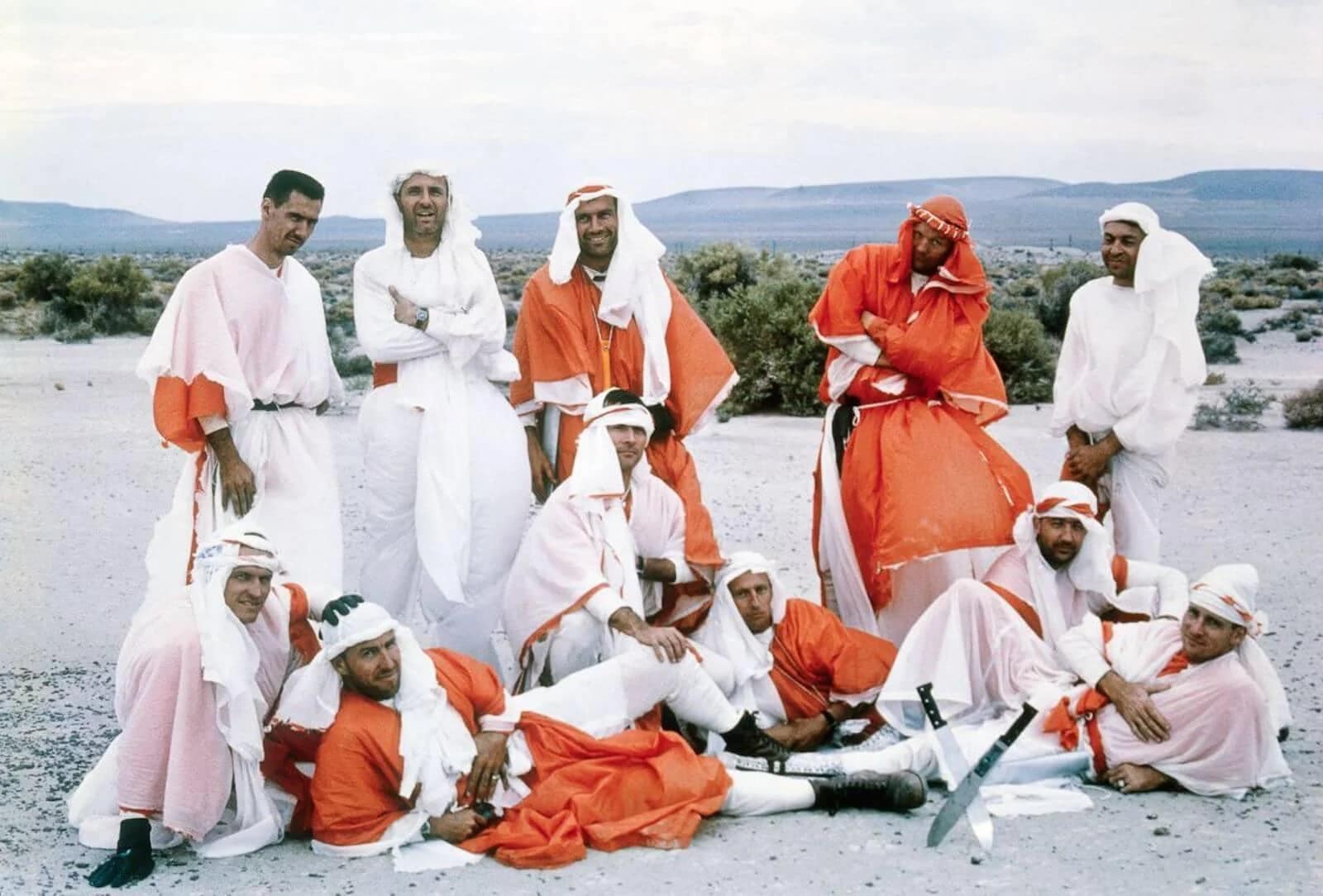 Gemini/Apollo astronauts pose during desert training at Stead Air Force Base in Nevada in 1964. They are (front row) Frank Borman; James A. Lovell; John W. Young; Charles Conrad; James A. McDivitt and Edward H. White. (Back row) Ray Zedehar (Astronaut Training Officer); Thomas P. Stafford; Donald K. Slayton; Neil A. Armstrong and Elliot M. See.